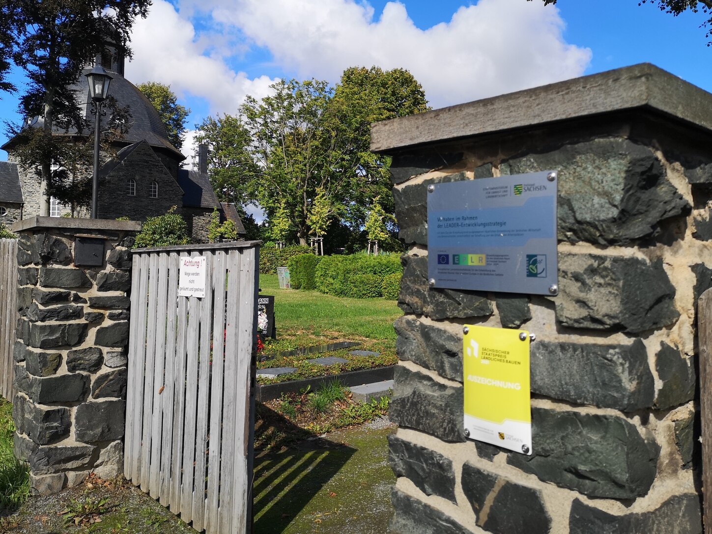 Friedhofseingang mit Fördervermerk an Säule