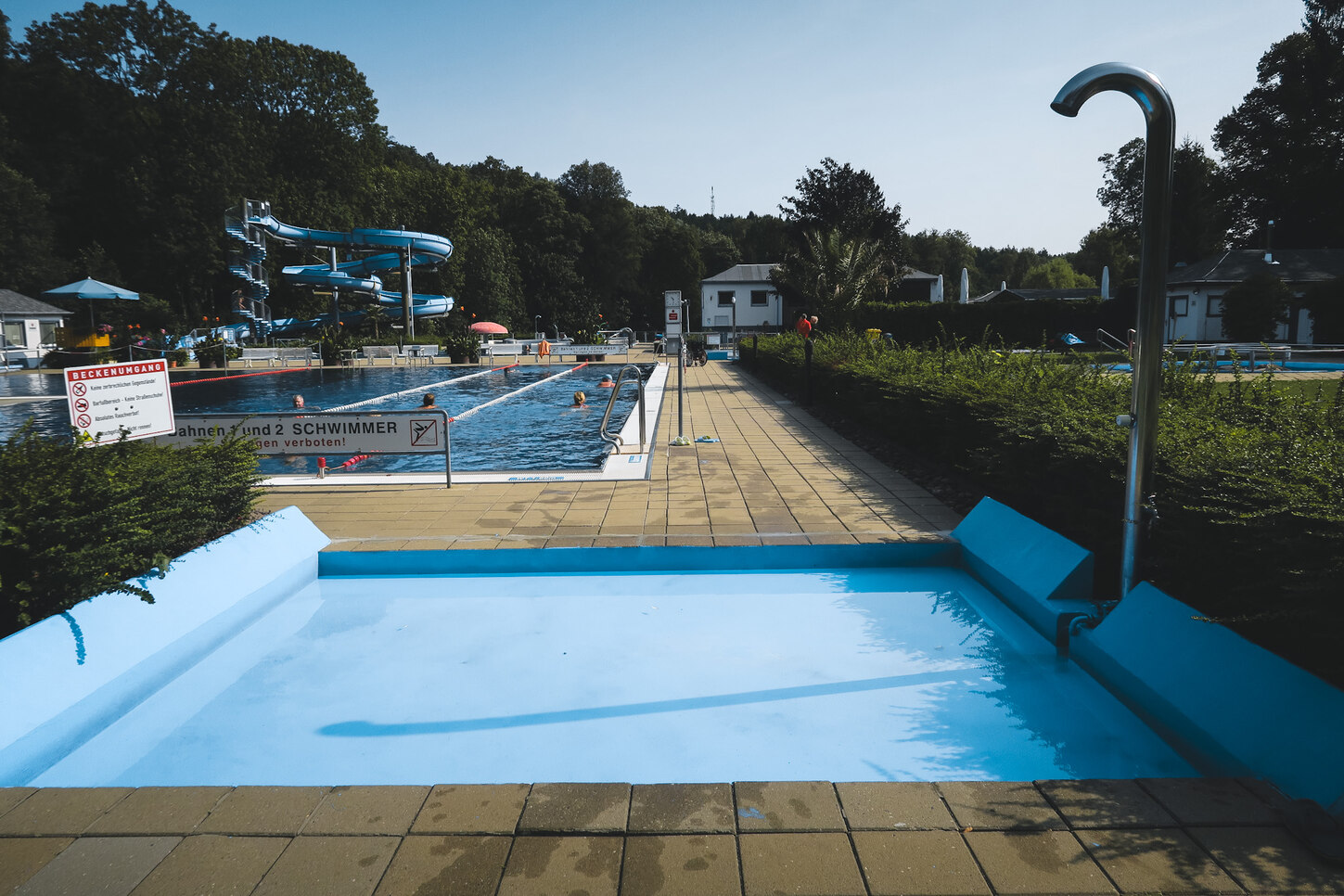 vorn im Bild das hellblaue Durchschreitebecken, im Hindergrund Blick in das Bad mit dem großen Schwimmbecken