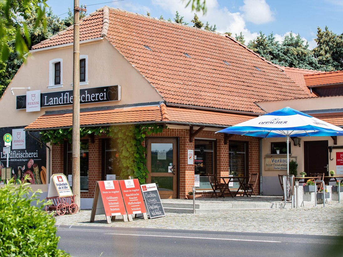 Blick auf die Landfleischerei mit Außenbereich zum Sitzen.